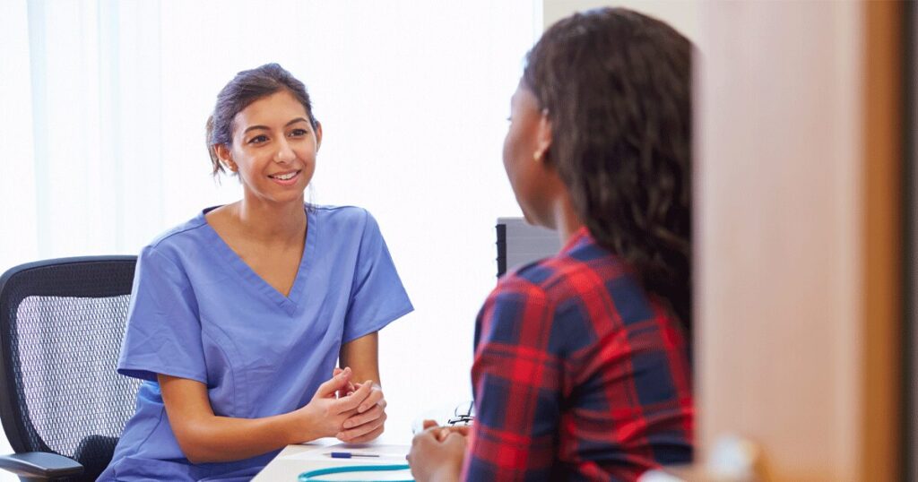 Compassionate healthcare professional meeting one-on-one with a woman in a private consultation room, listening attentively and providing guidance after a positive pregnancy test in a supportive, confidential setting.